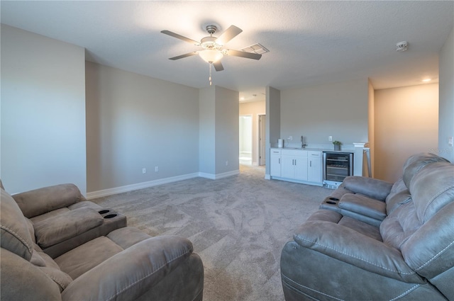 living room with a textured ceiling, light colored carpet, beverage cooler, and ceiling fan