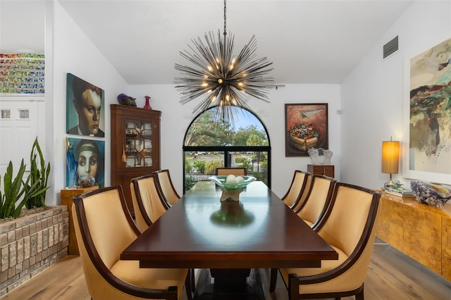 dining area featuring light wood-type flooring, an inviting chandelier, and lofted ceiling