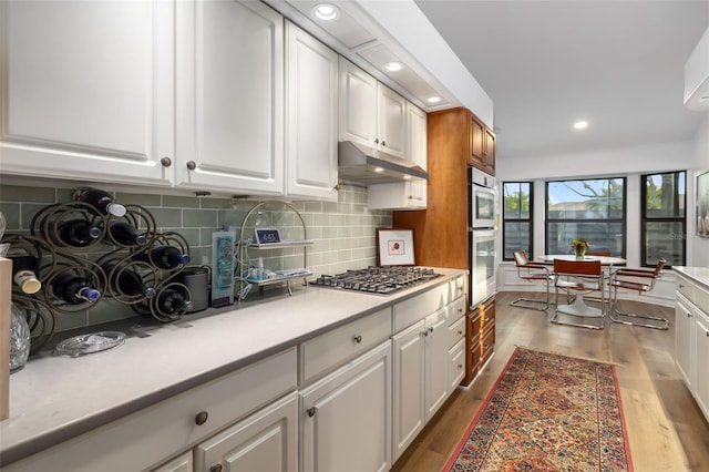 kitchen with white cabinets, decorative backsplash, light hardwood / wood-style floors, and appliances with stainless steel finishes