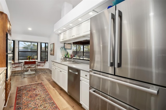 kitchen featuring sink, white cabinets, light wood-type flooring, and appliances with stainless steel finishes