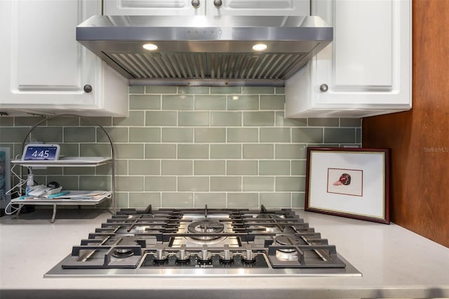 kitchen with tasteful backsplash, white cabinetry, extractor fan, and stainless steel gas stovetop