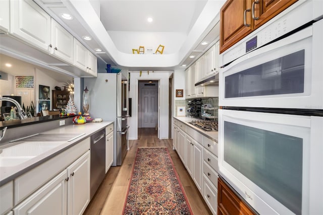 kitchen featuring sink, tasteful backsplash, light hardwood / wood-style floors, white cabinetry, and stainless steel appliances