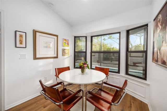 dining room featuring wood-type flooring and vaulted ceiling