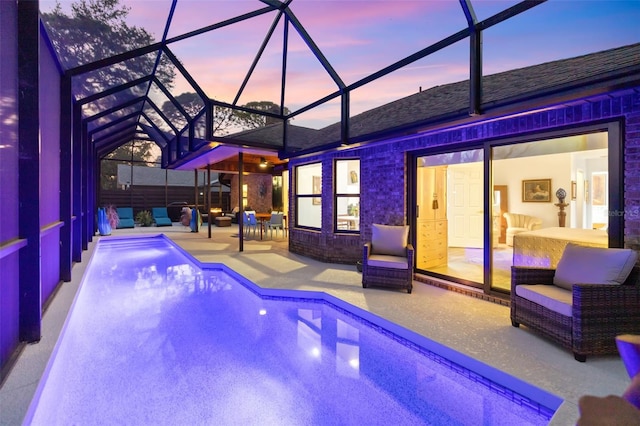 pool at dusk with a patio area and a lanai