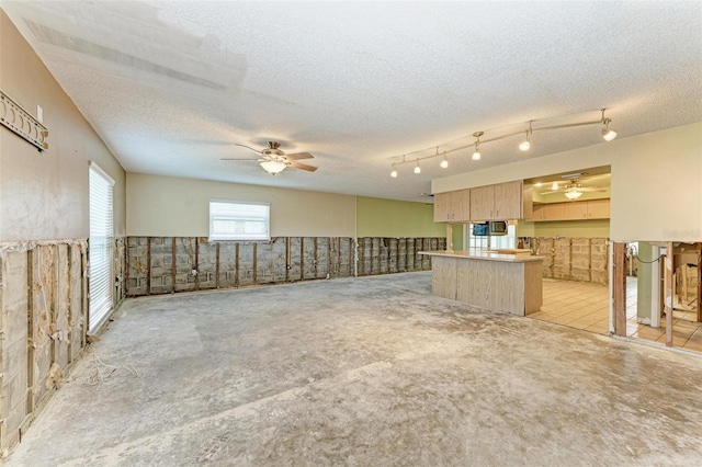 interior space featuring a breakfast bar, ceiling fan, a textured ceiling, light brown cabinetry, and kitchen peninsula