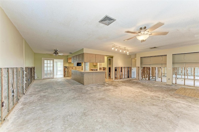 unfurnished living room with ceiling fan, a textured ceiling, and track lighting