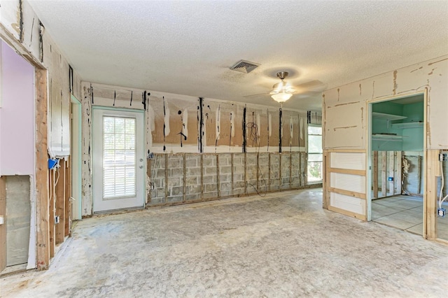 empty room with ceiling fan and a textured ceiling