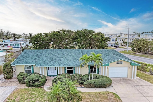 single story home featuring a garage, concrete driveway, roof with shingles, a residential view, and stucco siding