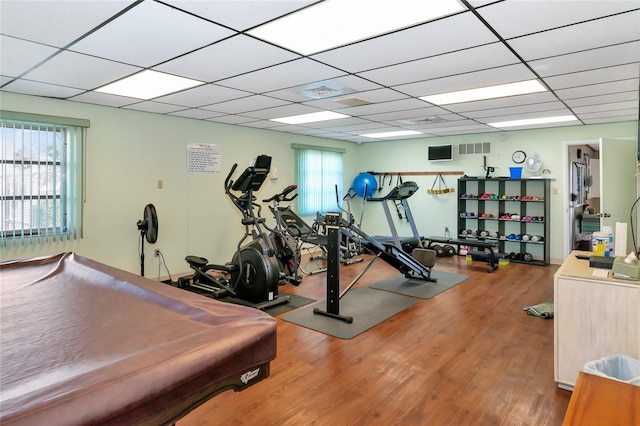 exercise room featuring plenty of natural light, wood-type flooring, and a drop ceiling