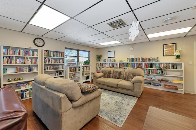 living room featuring a drop ceiling and dark hardwood / wood-style floors