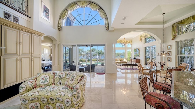 living room featuring decorative columns, a towering ceiling, and an inviting chandelier