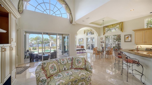 living room with a towering ceiling, a wealth of natural light, and sink