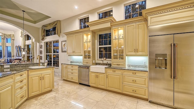 kitchen with light tile patterned floors, stainless steel appliances, dark stone counters, and sink