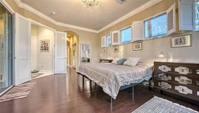 bedroom with hardwood / wood-style floors, a textured ceiling, an inviting chandelier, and ornamental molding