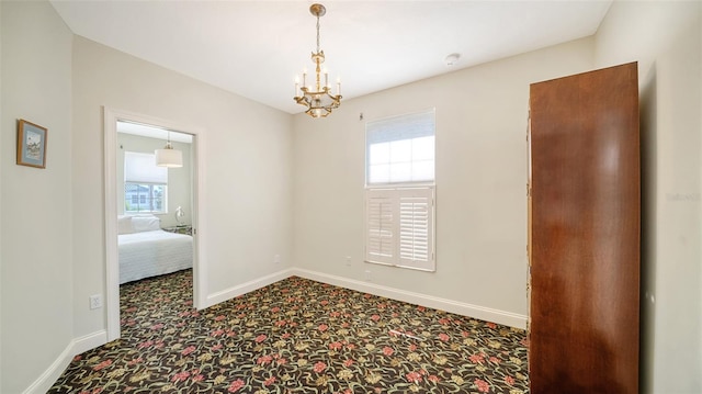 empty room featuring carpet and a chandelier