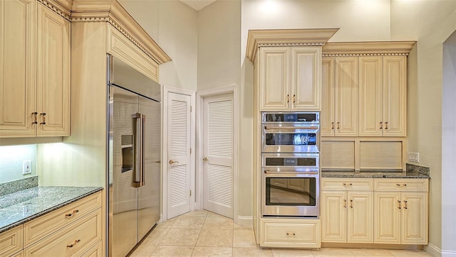 kitchen featuring light tile patterned floors, dark stone counters, and appliances with stainless steel finishes