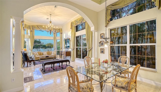 tiled dining area with ornate columns, crown molding, and an inviting chandelier