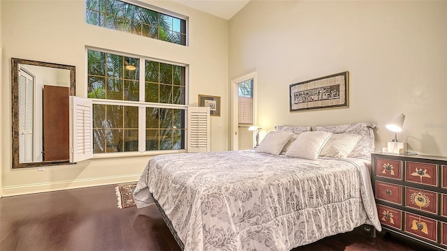 bedroom featuring dark wood-type flooring and high vaulted ceiling