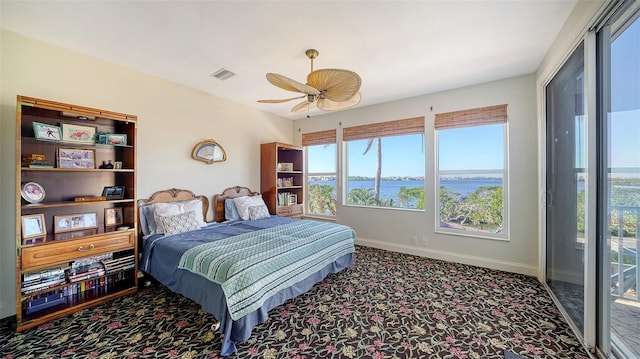 carpeted bedroom with access to outside, ceiling fan, and a water view