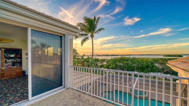 balcony at dusk featuring a water view