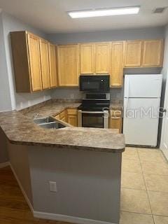 kitchen featuring kitchen peninsula, white fridge, light tile patterned flooring, and stainless steel stove