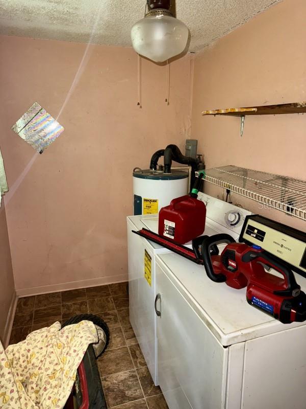 laundry area with washing machine and dryer, electric water heater, and a textured ceiling