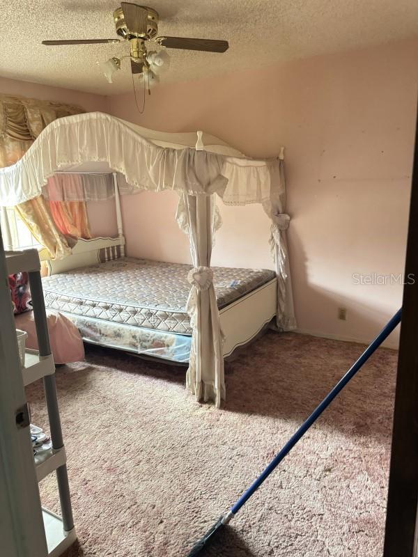 unfurnished bedroom featuring carpet flooring, a textured ceiling, and ceiling fan