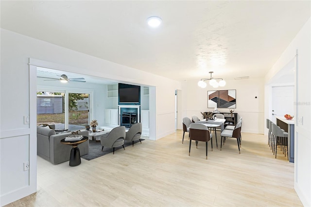 dining area featuring ceiling fan with notable chandelier and light hardwood / wood-style floors