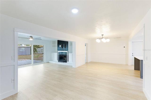 unfurnished living room with ceiling fan with notable chandelier and light wood-type flooring