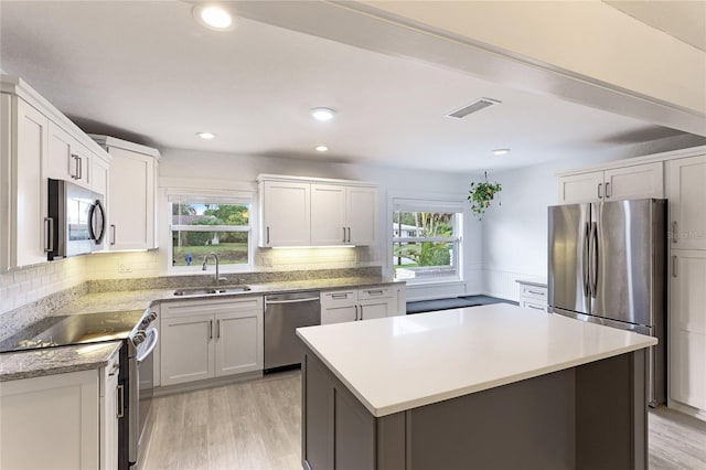 kitchen featuring a wealth of natural light, white cabinetry, sink, and appliances with stainless steel finishes