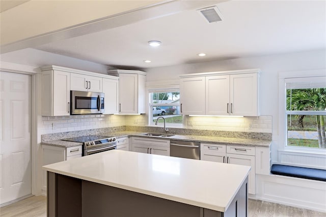 kitchen featuring white cabinetry, sink, light hardwood / wood-style flooring, and appliances with stainless steel finishes