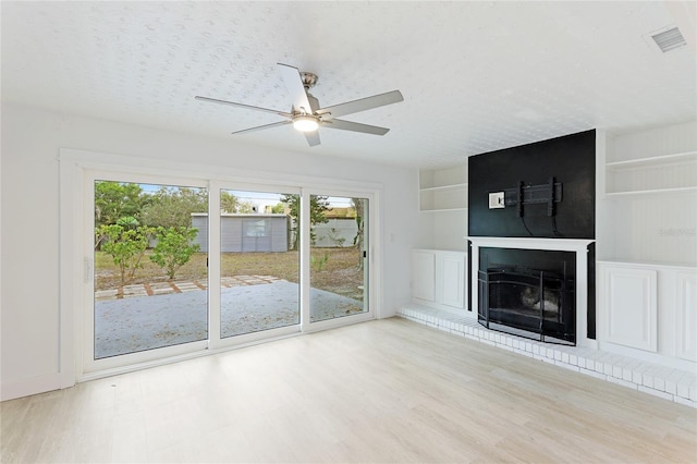 unfurnished living room featuring a large fireplace, light hardwood / wood-style floors, and a wealth of natural light