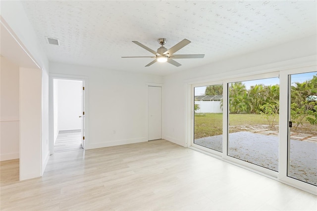 unfurnished room with ceiling fan, light hardwood / wood-style flooring, and a textured ceiling