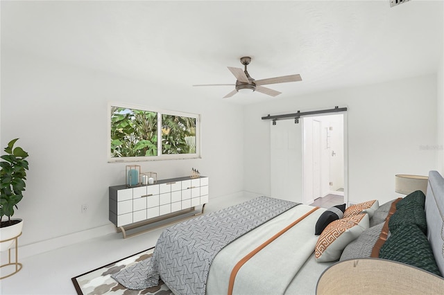 bedroom with ceiling fan, a barn door, and ensuite bathroom