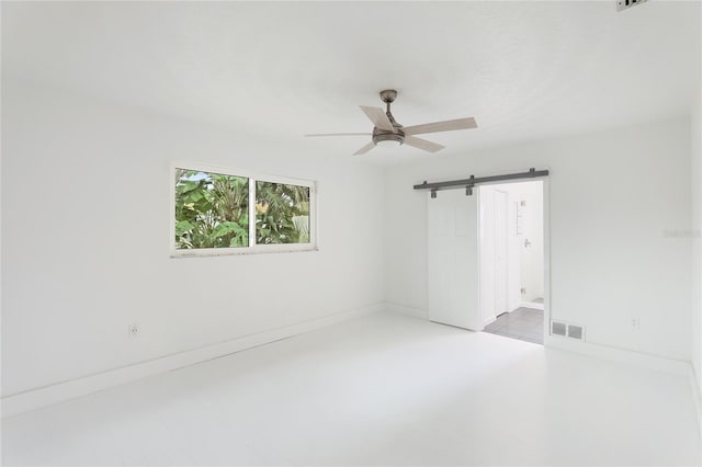 spare room with a barn door and ceiling fan