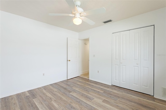 unfurnished bedroom featuring light wood-type flooring, a closet, and ceiling fan