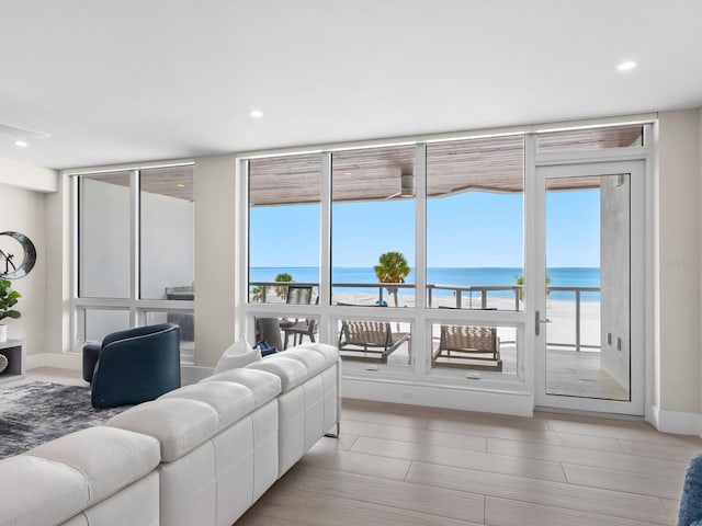 living room featuring a water view, a beach view, and floor to ceiling windows