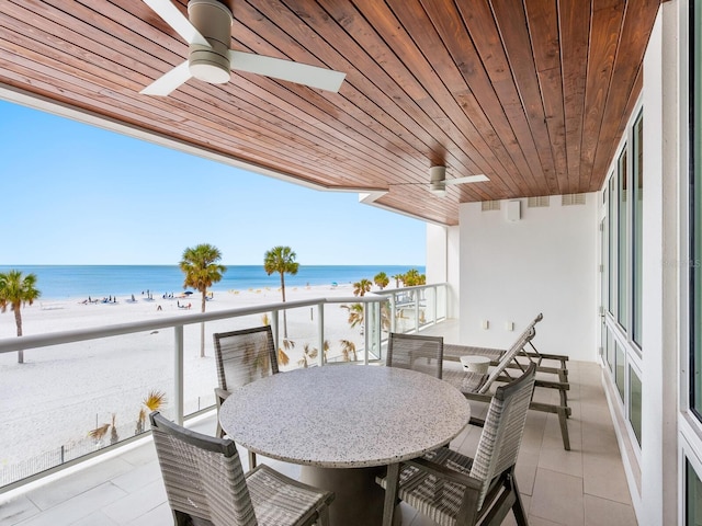 balcony with a water view, ceiling fan, and a beach view