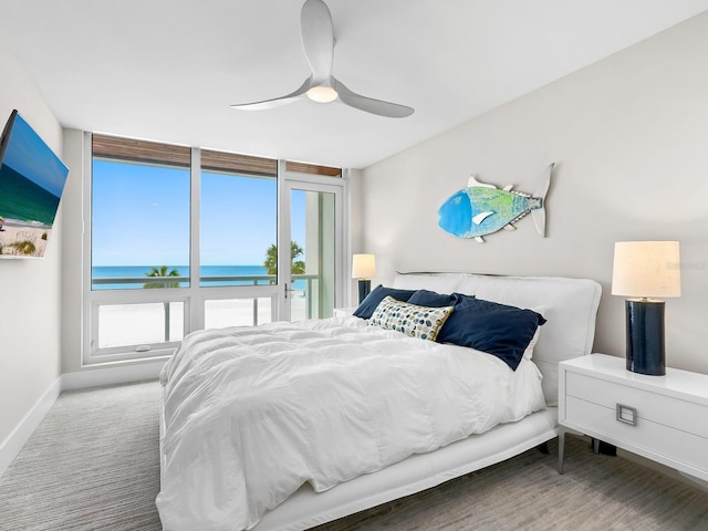 carpeted bedroom featuring a water view and ceiling fan