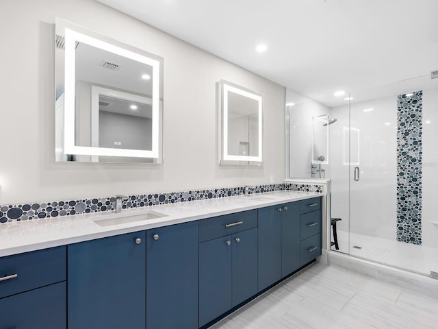 bathroom with vanity, a shower with shower door, and decorative backsplash