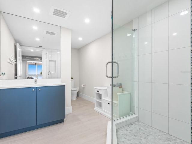 bathroom featuring a shower with door, vanity, wood-type flooring, and toilet