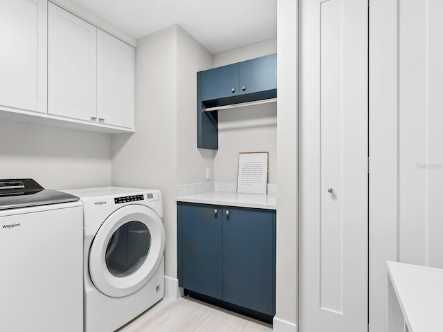 laundry room featuring independent washer and dryer, cabinets, and light wood-type flooring