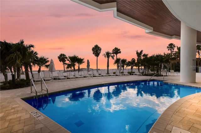 pool at dusk with a patio area