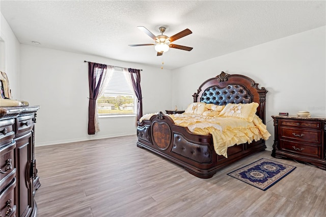 bedroom with ceiling fan, a textured ceiling, and light hardwood / wood-style flooring