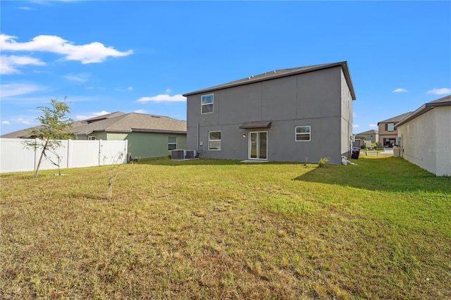 back of property with central AC unit and a yard