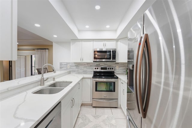 kitchen with decorative backsplash, light stone counters, stainless steel appliances, sink, and white cabinets