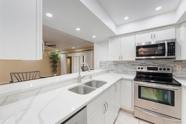 kitchen with white cabinets, light stone counters, sink, and stainless steel appliances