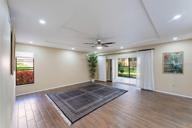 interior space featuring a raised ceiling, ceiling fan, and dark wood-type flooring