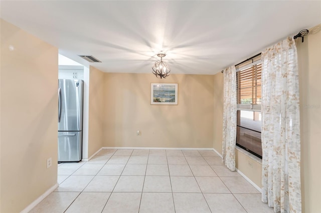 unfurnished room with a notable chandelier and light tile patterned floors