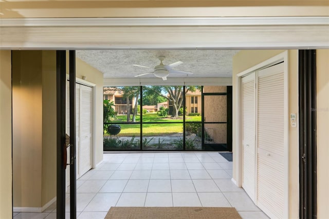 interior space featuring ceiling fan, light tile patterned floors, and a textured ceiling